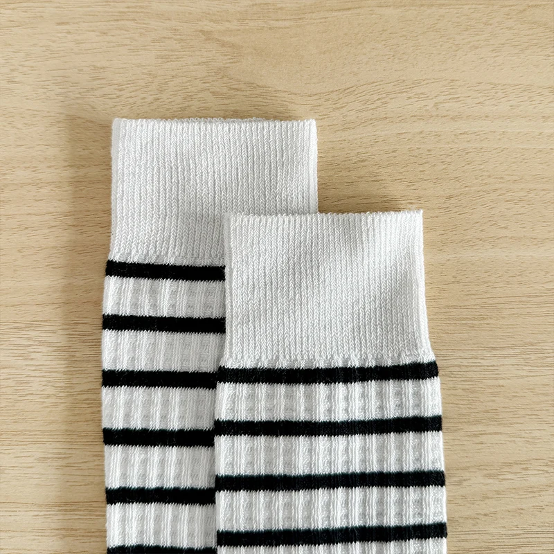 une paire de chaussettes pour fille simples et polyvalentes avec un design patchwork noir et blanc pour le printemps et l'automne. une paire de chaussettes pour fille simples et polyvalentes avec un design patchwork noir et blanc pour le printemps et l'automne.
