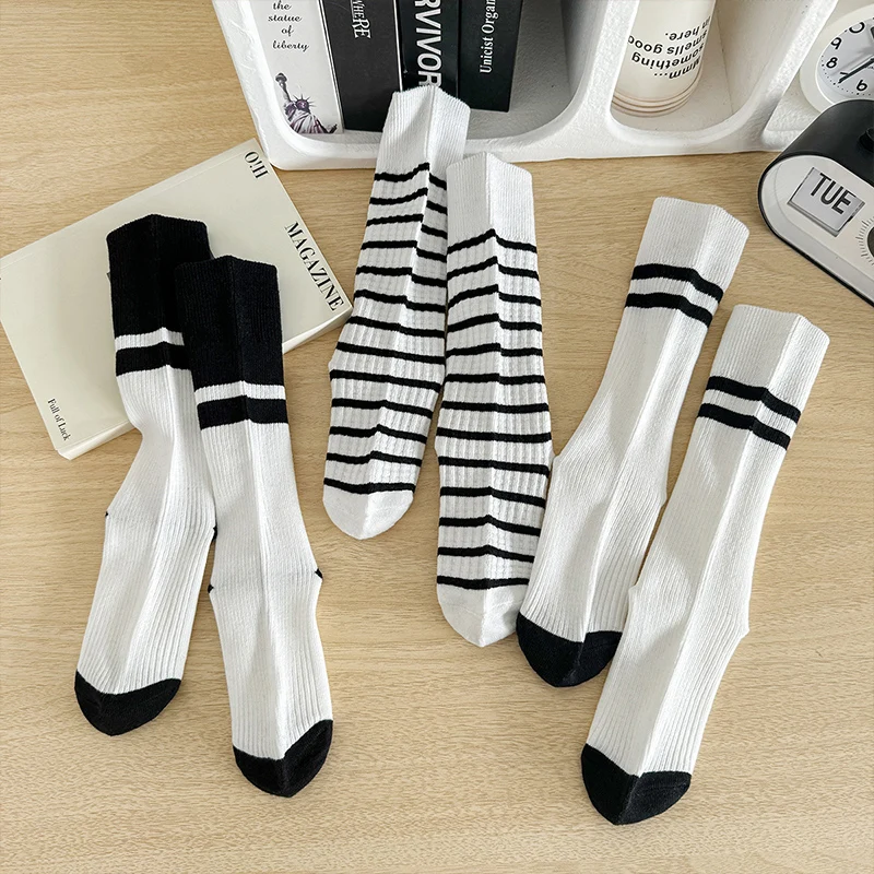 une paire de chaussettes pour fille simples et polyvalentes avec un design patchwork noir et blanc pour le printemps et l'automne. une paire de chaussettes pour fille simples et polyvalentes avec un design patchwork noir et blanc pour le printemps et l'automne.
